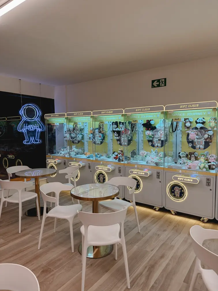 Zona de bar con una máquina de peluches y algunas sillas para los clientes.