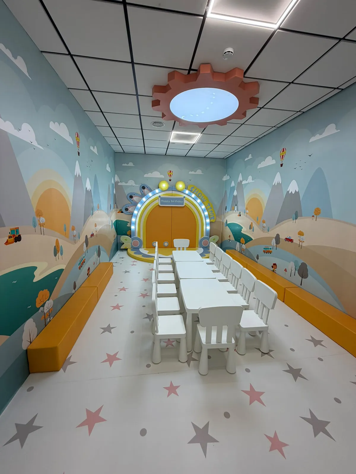 Sala privada de cumpleaños con mesas blancas, bancos amarillos y decoración de invierno en Amazing Park Sants.